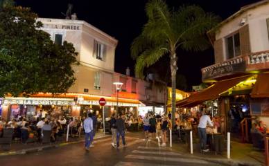 Centre-ville de Juan-Les-Pins illuminé la nuit, avec des personnes se promenant et profitant de l'animation nocturne